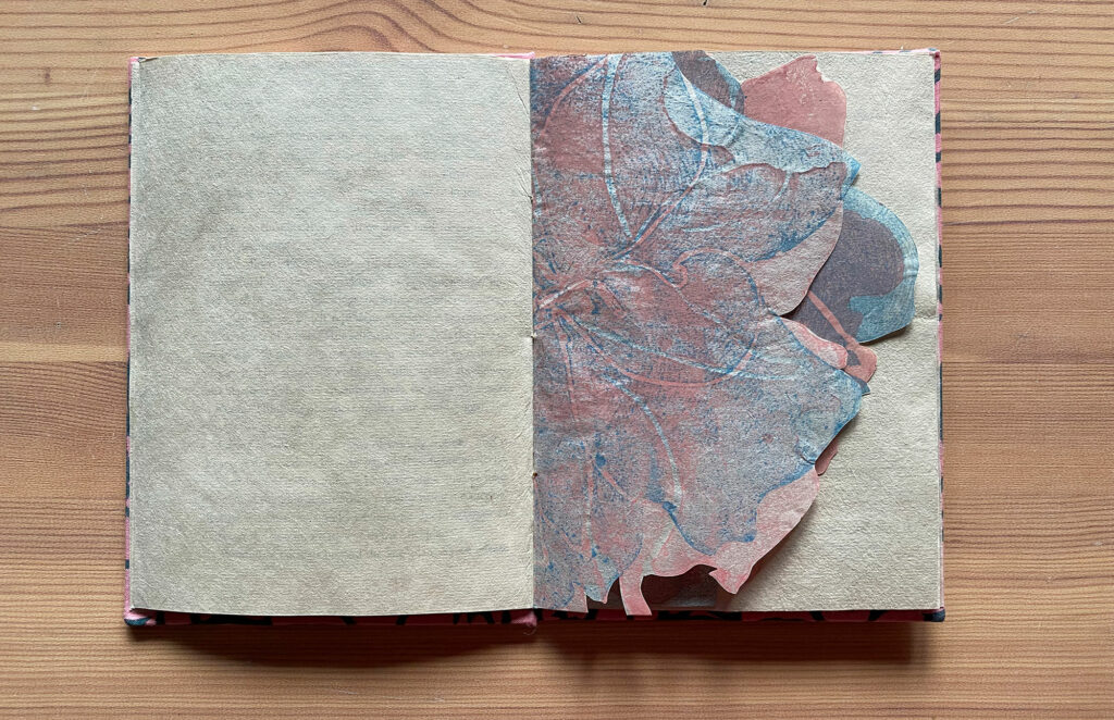 open book showing center spread of a cutout of a blue and pink cherry blossom flower, Untitled artist’s book, 2020, Artist’s book, single section case binding structure, pages are made with archival Okawara paper, woodcut prints on endsheets and spread on Kitakata paper